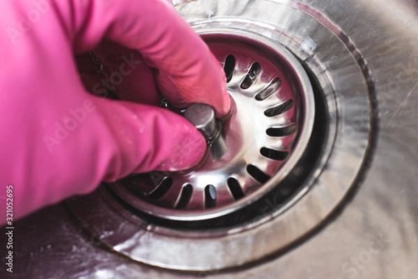 Obraz Man in pink glove plugs cork in sink for dishwashing. Save water