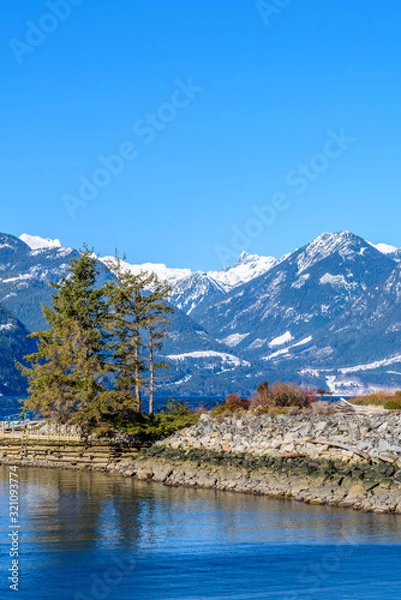 Fototapeta Fantastic view over ocean, snow mountain and rocks at Furry Creek Dive Site in Vancouver, Canada.