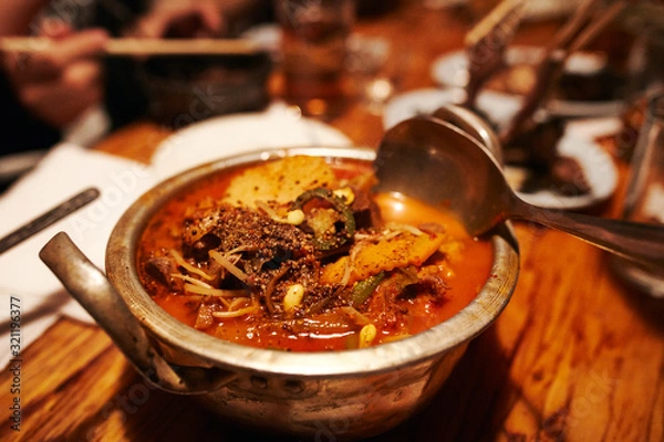 Obraz Korean Style Spicy Beef Soup with herbs in Tin Pot