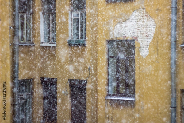 Fototapeta facade of an old yellow house in heavy snow before a storm