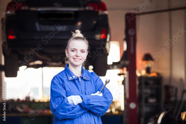 Fototapeta Successful woman mechanic with wrench is smiling