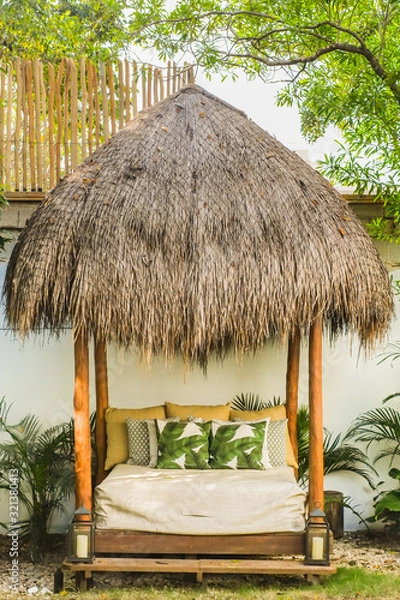Fototapeta Straw hut bed to relax in backyard at an AirBnB after a day at the beach. Tropical vibes for nap time by the pool.