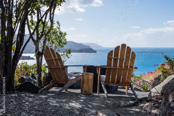 Fototapeta Pair of adirondack chairs looking onto Little Bay beach in Tortola BVI. Little gas fire pit to be fired up to enjoy the view.