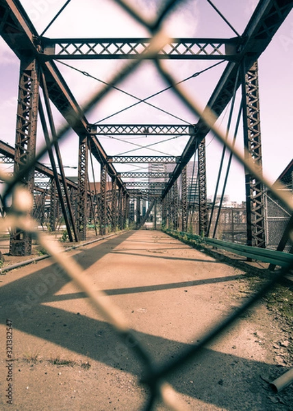 Fototapeta Chain-linked fence looking at the Old Northern Ave Bridge in Boston, MA.