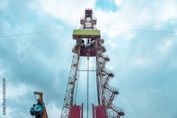 Obraz Oil and Gas Drilling Rig onshore dessert with dramatic cloudscape. Oil drilling rig operation on the oil platform in oil and gas industry
