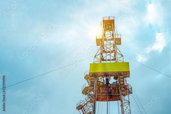 Fototapeta Oil and Gas Drilling Rig onshore dessert with dramatic cloudscape. Oil drilling rig operation on the oil platform in oil and gas industry