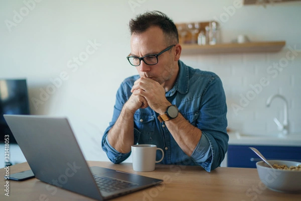 Fototapeta Thoughtful serious young man lost in thoughts in front of laptop, focused businessman thinking of problem solution, worried puzzled man looking ar laptop screen