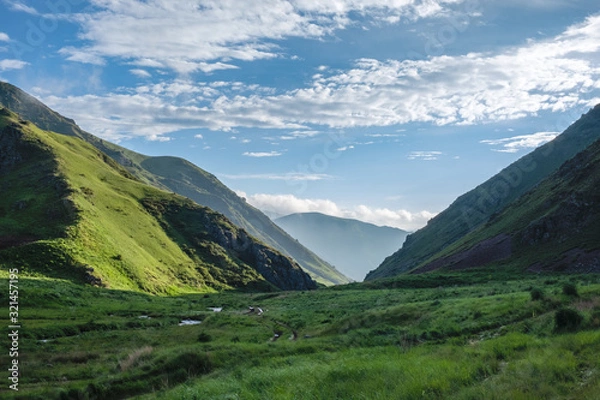 Fototapeta Beautiful landscape of green mountain valley with dramatic cloudy sky background.