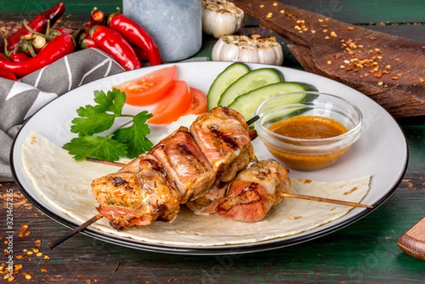 Fototapeta Kebab of turkey in bacon with fresh vegetables.