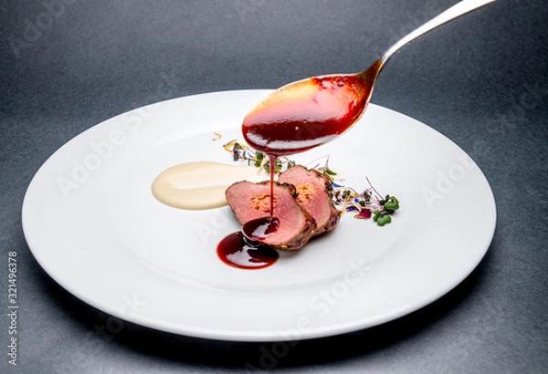 Obraz Meat fillet covering with sauce on a white plate