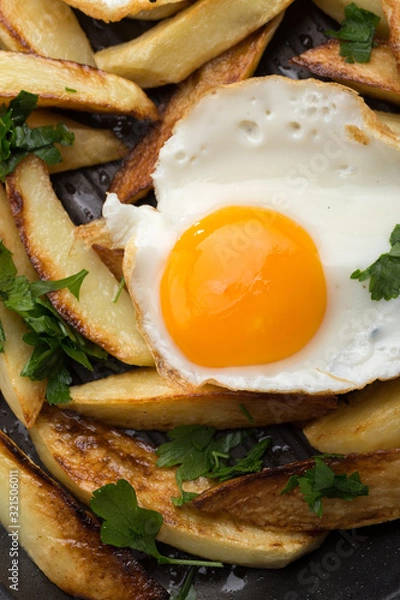 Obraz Breakfast in the pan. Fried potatoes with eggs in a skillet. Food bachelor. Cooked by a man. Hot and fresh. Homemade breakfast on black table. Fried eggs and sweet potato hash in cast iron skillet Fre