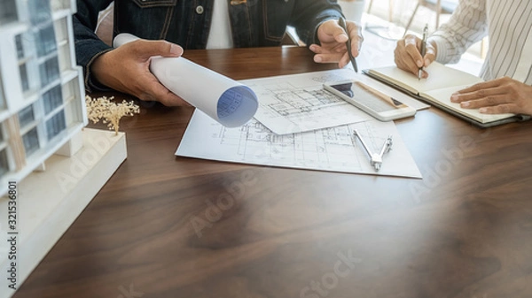 Fototapeta Engineer or architect teamwork working on construction project with building model and blueprint in office. Construction concept.