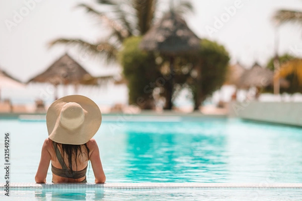 Fototapeta Kobieta relaks przy basenie w luksusowym kurorcie hotelowym, ciesząc się doskonałymi wakacjami na plaży