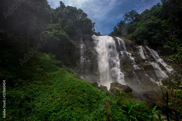 Fototapeta The abstract blurry background of the nature of water droplets from scattered waterfalls covering grass and stone surfaces, the beauty of spontaneous ecosystems.