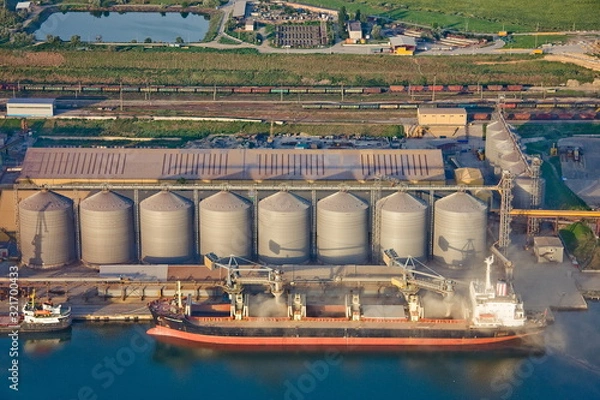 Fototapeta   loading a ship with grain in the seaport.aerial conveyour grain industry loading port sea shiploader silo storehouse transport transhipment trade berth handling