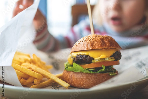 Fototapeta child eats a mini Burger and fries. children's menu in the cafe