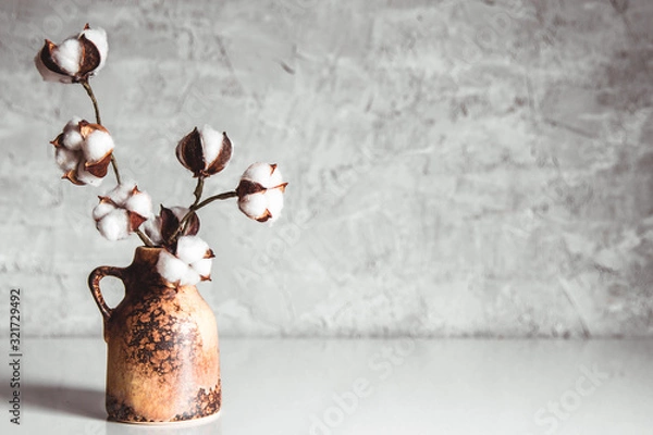 Fototapeta branches of cotton in a brown wicker vase on a background of a gray-blue wall