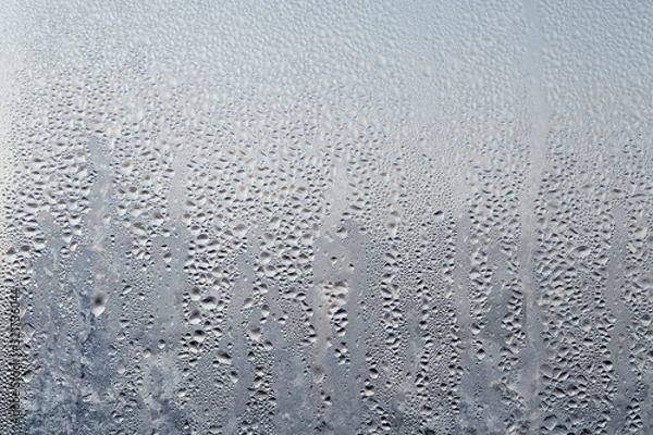 Obraz Frozen drops of condensed steam water drops on the transparent window glass. Clean background. Condensation of moisture at extreme temperatures. Water vapor condenses on cold window glass and freezes