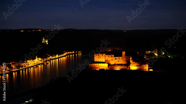 Fototapeta Night shot of Castle Rheinfels, colorfully illuminated, in front of the Rhine valley and under a starry sky. In background Castle Katz and the city of St.Goar