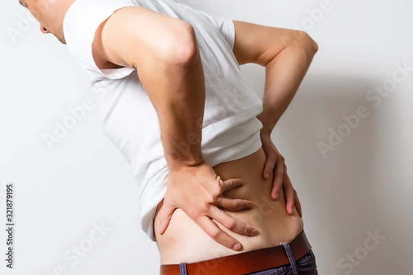 Fototapeta Lumbago symptom. Young man holding his painful inflamed loin. Health care and medicine.