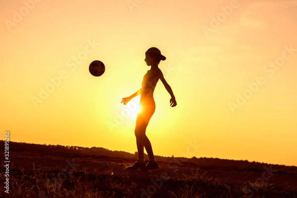 Fototapeta Boy playing with ball in nature in hot evening, silhouette of playing child at sunset in countryside
