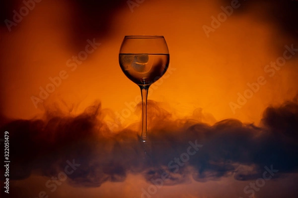 Fototapeta Cocktail in a glass wine glass with smoke burns on a Lush Lava background. Close up