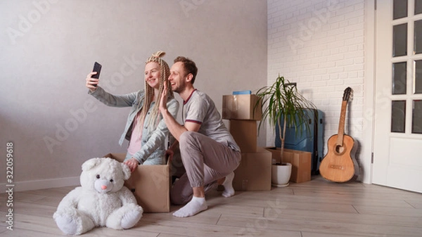 Obraz Young married couple calls friends or relatives via video, moves to a new apartment or city