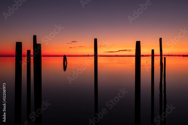 Obraz A long exposure photo of pylons in the sea at sunset with Venice in the background