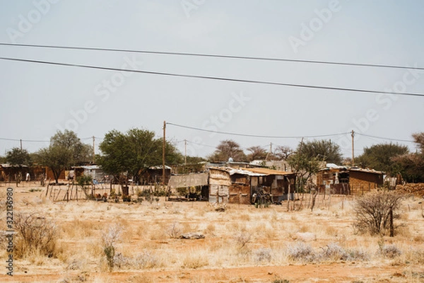 Fototapeta shacks outside in the desert between sand and bushes in Africa