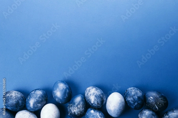Fototapeta Beautiful group ombre blue Easter eggs with quail eggs and feathers on a blue background. Easter concept. Border eggs. Copy space for text