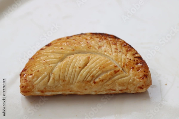 Fototapeta one apple turnover with feather pattern etched on it with white background
