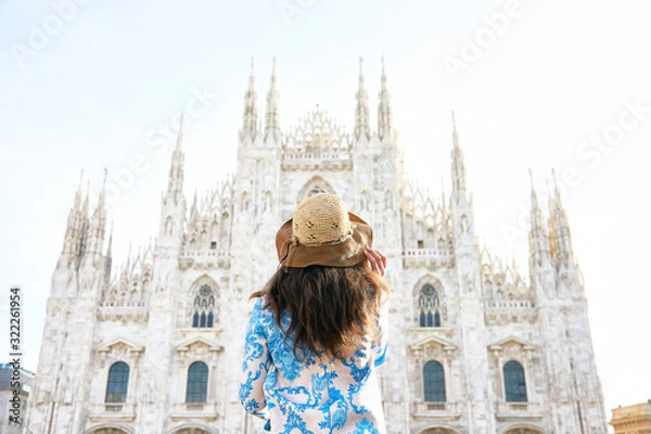 Fototapeta Travelver with a hat looking the front of Milan Duomo in Italy during the day