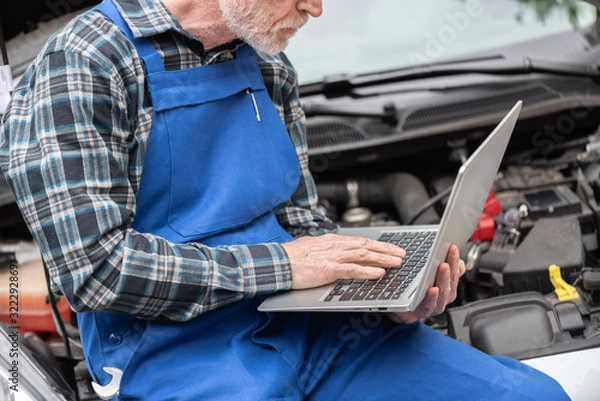 Fototapeta Mechanic using laptop for checking car engine