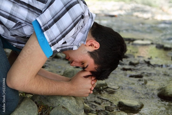 Obraz Man Praying by Creek