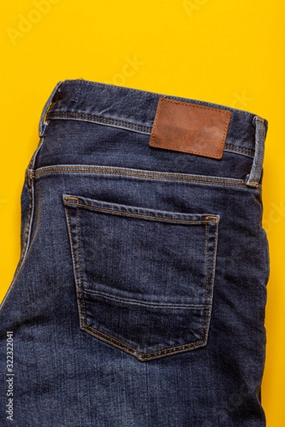 Fototapeta Back of blue jeans texture. Denim jeans pocket texture on a yellow background