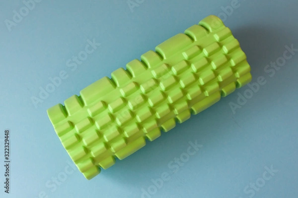 Obraz Sport green foam roller on blue background. Fitness background.