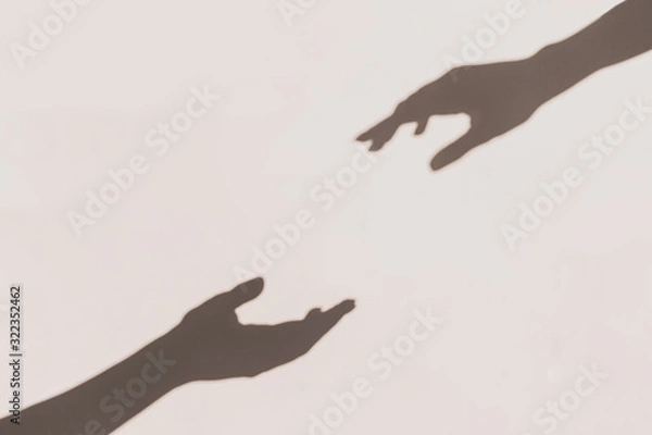 Fototapeta Grey shadows of hands reaching each other on the wall. Abstract blurred effect.