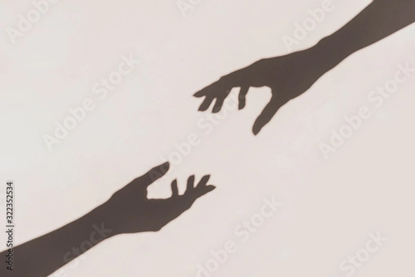 Fototapeta Grey shadows of hands reaching each other on the wall. Abstract blurred effect.