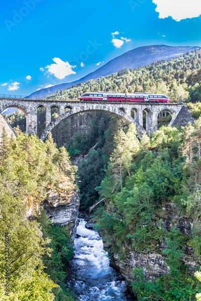 Fototapeta VERMA, NORWAY - 2018 AUGUST 01. Kylling bridge with the river below and train on the top.