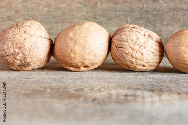 Fototapeta Close-up healthy chopped and unshelled walnuts on a wooden old table. Vegetarian food