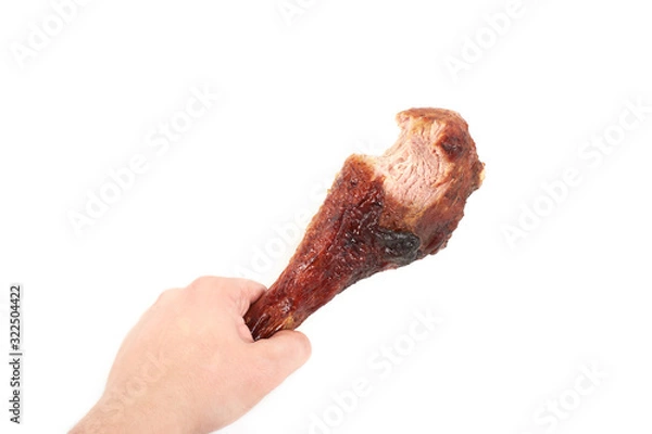 Fototapeta hand holding roasted turkey leg with bite taken , isolated on white background.