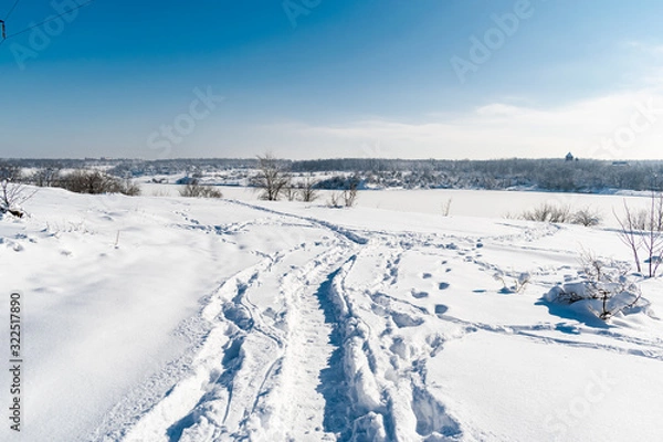 Fototapeta Spacious snow landscape. River and hills in Russia, white winter on the terrain, a lot of fluffy snow and ice under a beautiful blue sky. Rostov region, town of Shakhty, the river Grushevka
