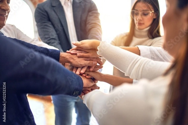 Fototapeta Group of business workers standing with hands together at the office
