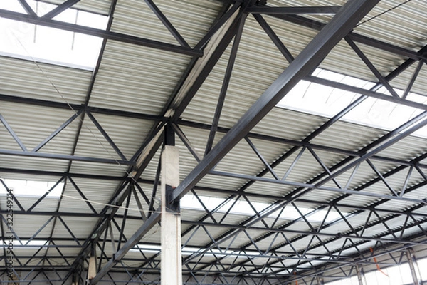 Fototapeta Aluminum roof with windows on a metal frame. A concrete column holds the structure. Construction of the hangar.