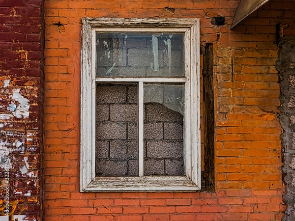 Fototapeta A walled window with broken glass in the wall of a brick house