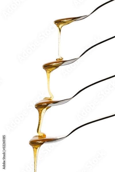 Obraz honig fliesst über vier löffel vor weissem hintergrund