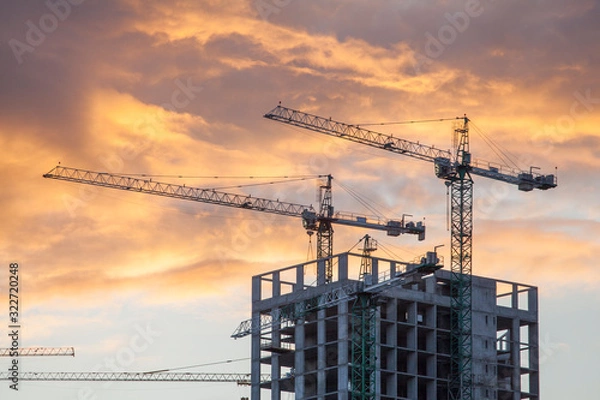 Fototapeta construction site with cranes against the background of bright evening clouds