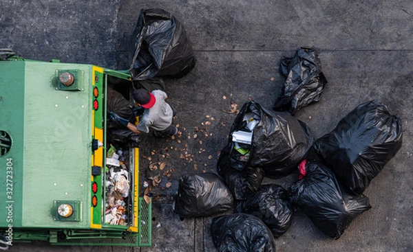 Fototapeta Green garbage truck And the employees are collecting a lot of black garbage bags that are tied up On the sidewalk To discard Viewed from the top view on 06/02/2020 Bangkok Noi, Bangkok. Thailand