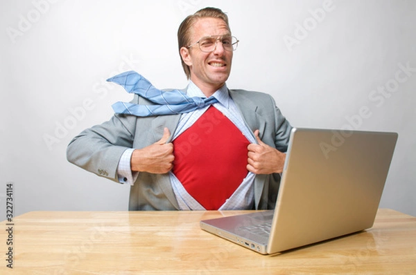 Fototapeta Superhero tech businessman giving a cheeky wink to the camera as he gets ready to save the day from his office desk