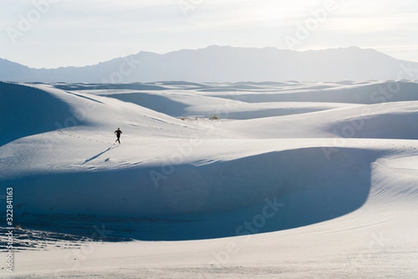 Fototapeta A man running on the sand dunes at White Sands National Park in Alamogordo, New Mexico. 